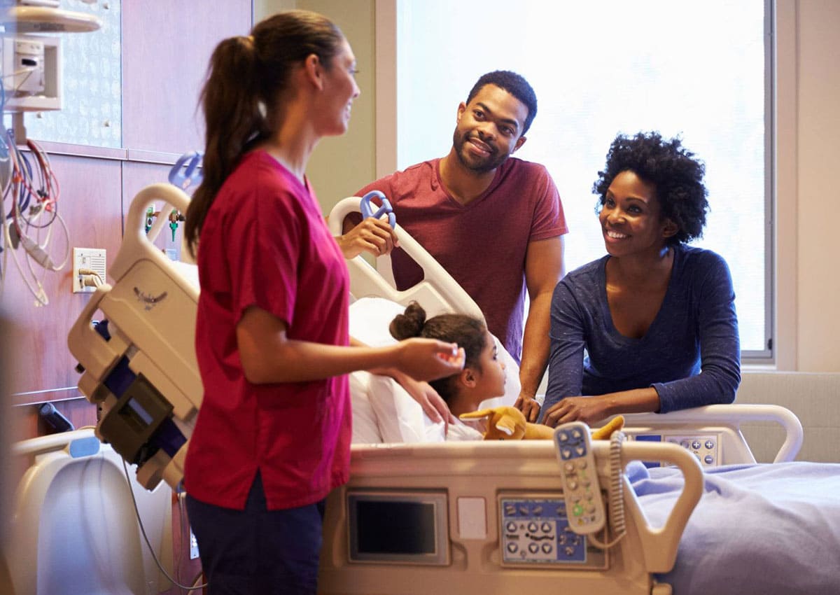 pediatrician visiting parents and child in hospital bed