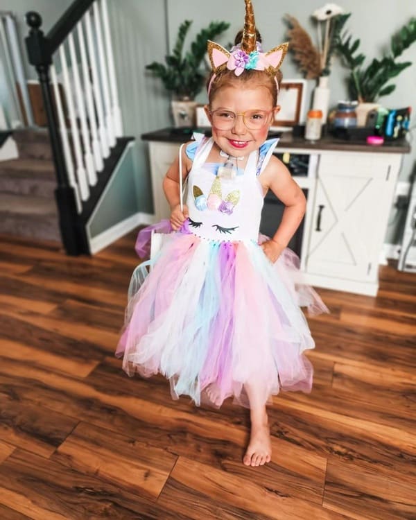 Young pediatric homecare patient standing and smiling in a colorful tutu and a unicorn headband 