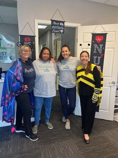 Four women stand and smile at the camera, one dressed as a bee, another dressed as a butterfly