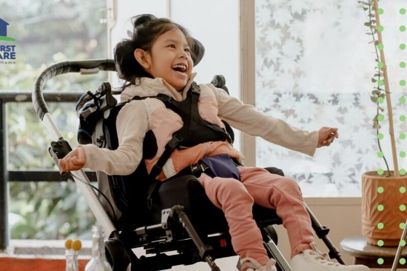 A pediatric homecare patient wearing pink smiling in her wheelchair