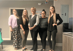 Five women stand and smile at the camera