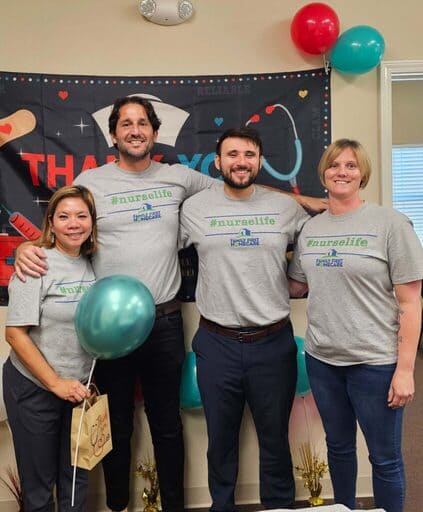 Four nurses wearing #nurselife tshirts smile at the camera 