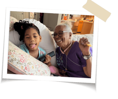 A nurse smiling on the couch with her pediatric care patient 