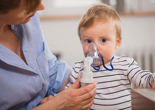 Woman holding a young pediatric homecare patient doing a breath treatment